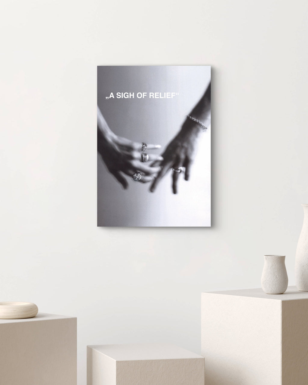 Canvas print with hands holding a heart shape on a white wall above a table with vases.