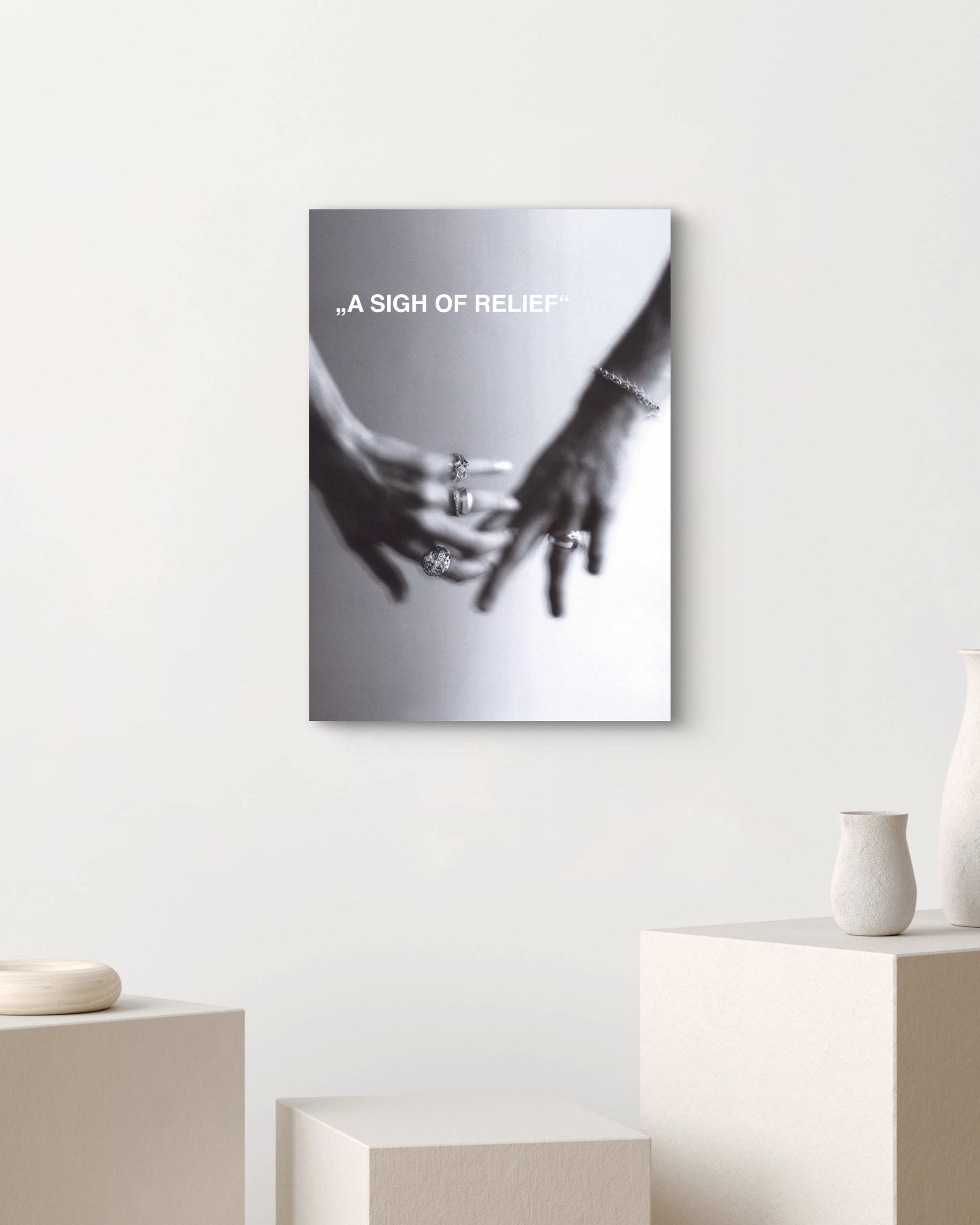 Canvas print with hands holding a heart shape on a white wall above a table with vases.